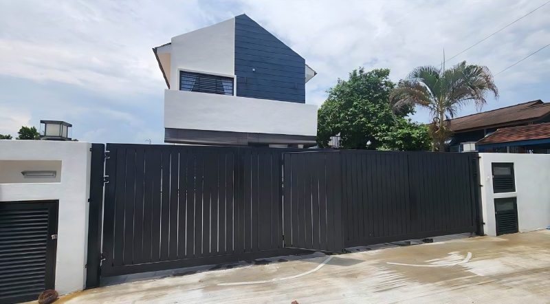 Bungalow with dark clad upper volume behind the gate