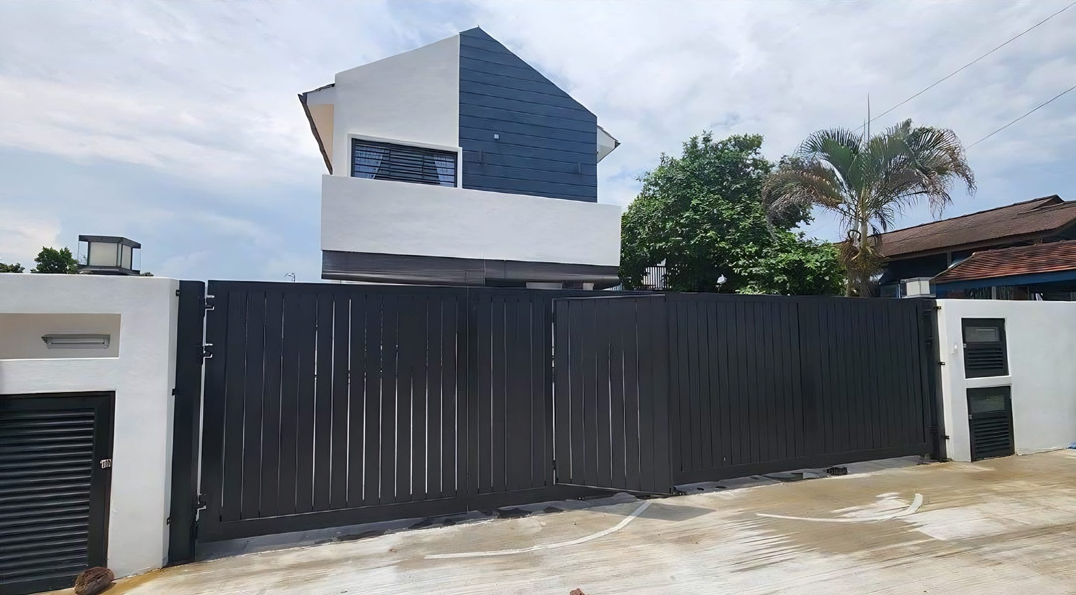 Bungalow with dark clad upper volume behind the gate