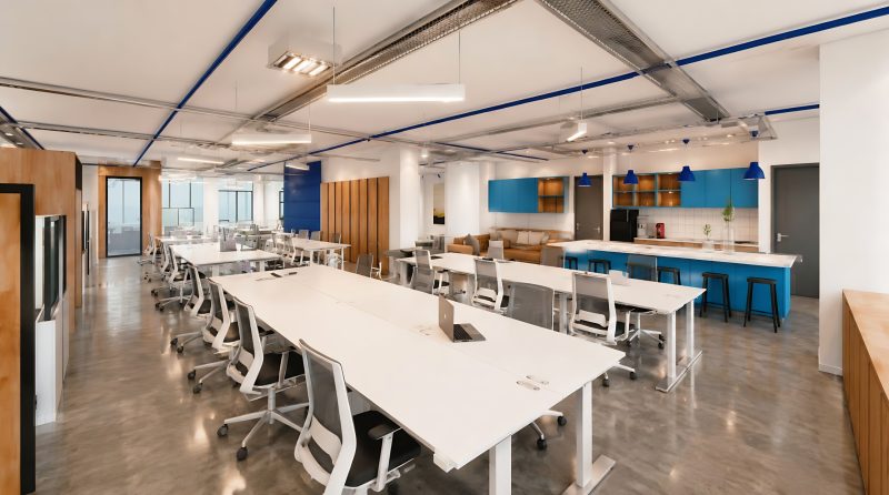 Open-plan office with long white desks and blue accents