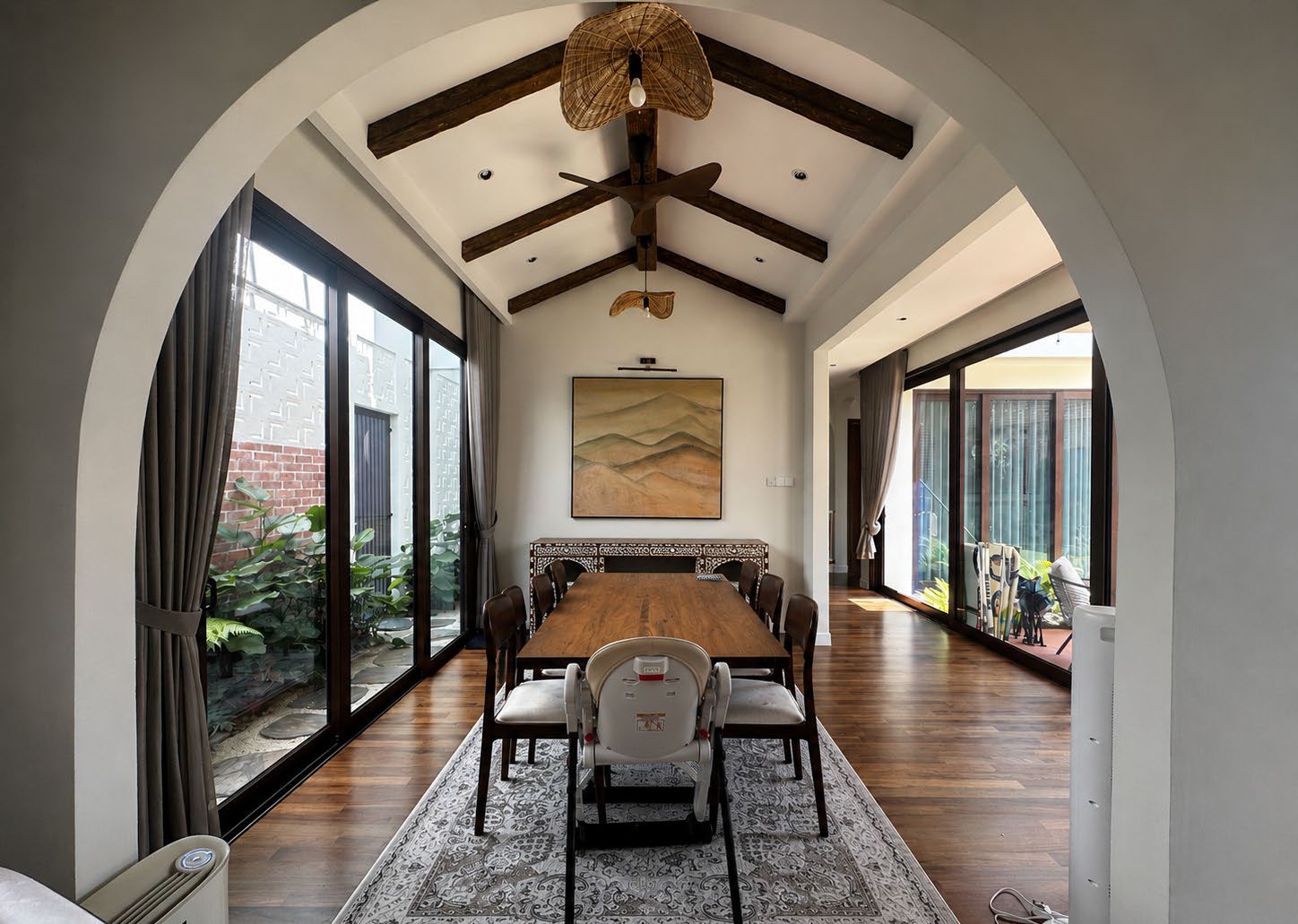 Dining room under a timber-beamed ceiling, seen through an arch