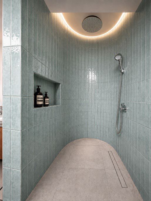 Pale green tiled shower with curved ceiling light